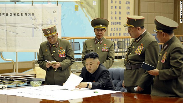 Kim Jong Un confers with his Generals under a sign that says 'Plan to defeat the United States' conceived after watching Boris and Natsha on the Rocky and Bullwinkle Show