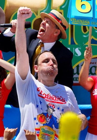 Joey Chestnut lifts his arm to make more room for another 'dog'